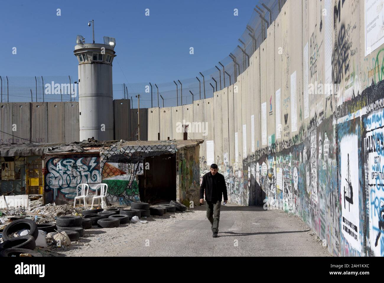 Bethlehem, West Bank. 23 Dez, 2019. Eine palästinensische Spaziergänge Die bside Israel Trennwand in die biblische Stadt Bethlehem, West Bank, am Montag, 23. Dezember 2019. Eine neue Art der Arbeit mit der Überschrift "Auto von Bethlehem" durch Graffiti Künstler Banksy, zeigt eine Krippe vor dem israelischen Trennungsmauer, ist an seinem Walled-Off Hotels in der Nähe angezeigt. Foto von Debbie Hill/UPI Quelle: UPI/Alamy leben Nachrichten Stockfoto