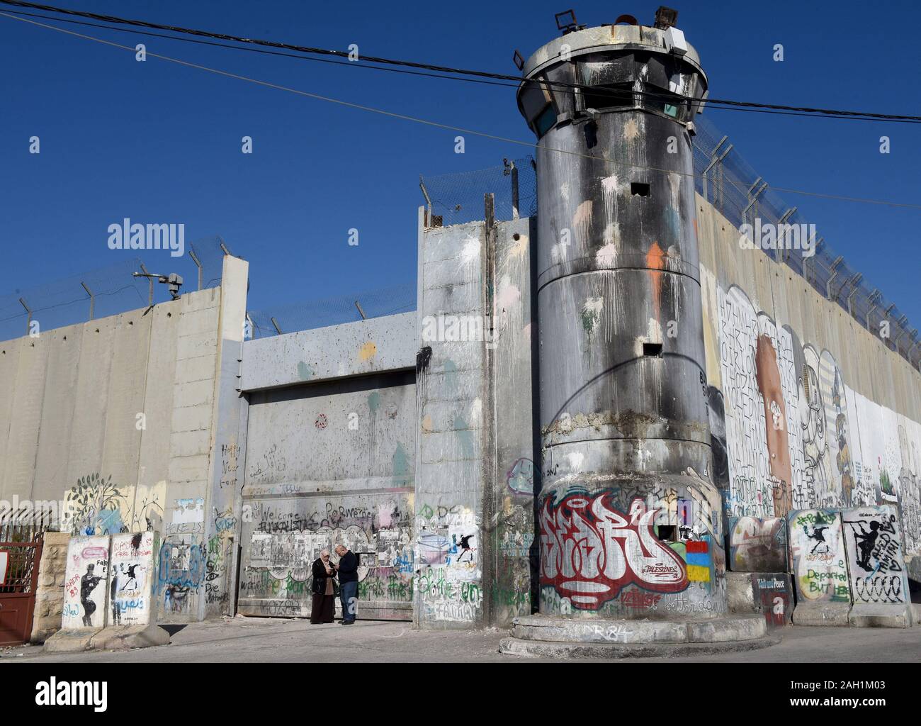 Bethlehem, West Bank. 23 Dez, 2019. Die palästinenser stehen neben einem israelischen Wachturm in der Trennwand in der biblischen Stadt Bethlehem, West Bank, am Montag, 23. Dezember 2019. Eine neue Art der Arbeit mit der Überschrift "Auto von Bethlehem" durch Graffiti Künstler Banksy, zeigt eine Krippe vor dem israelischen Trennungsmauer, ist an seinem Walled-Off Hotels in der Nähe angezeigt. Foto von Debbie Hill/UPI Quelle: UPI/Alamy leben Nachrichten Stockfoto