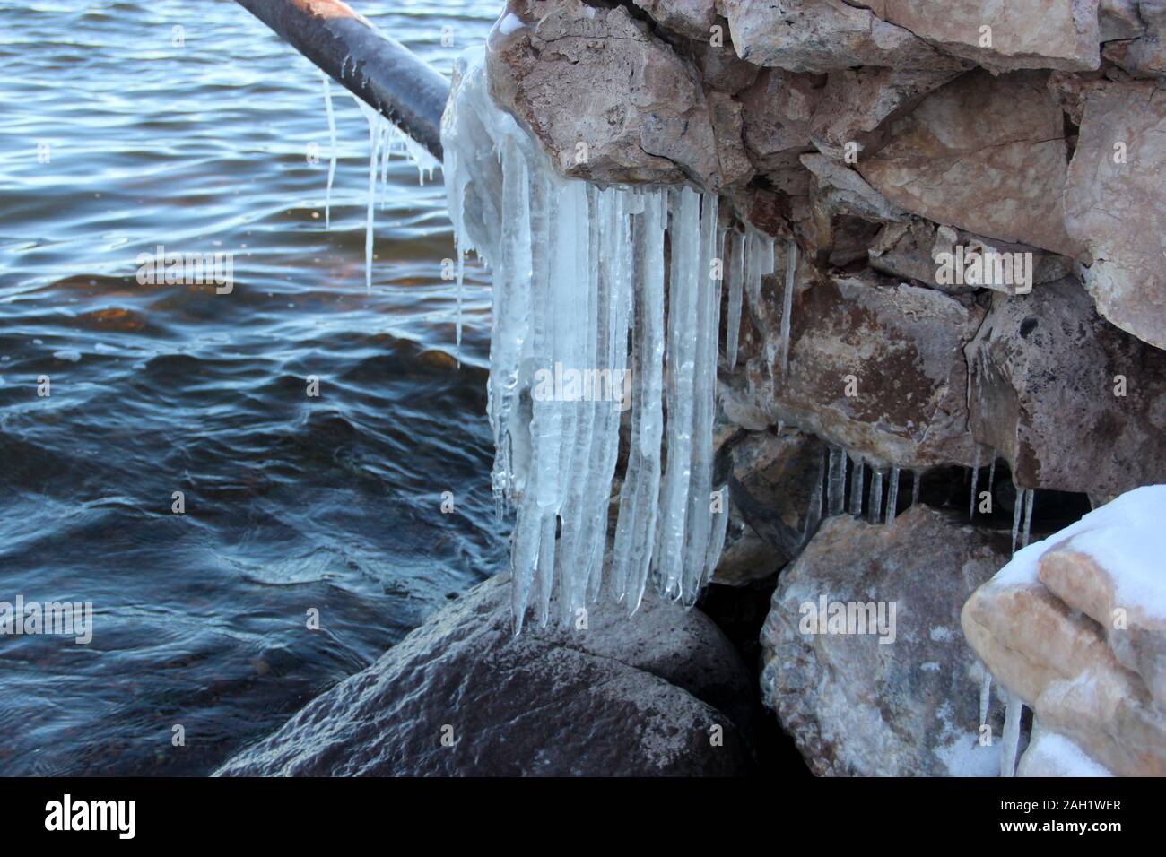 Eiszapfen hängen von einem Rock & Leitung Stockfoto