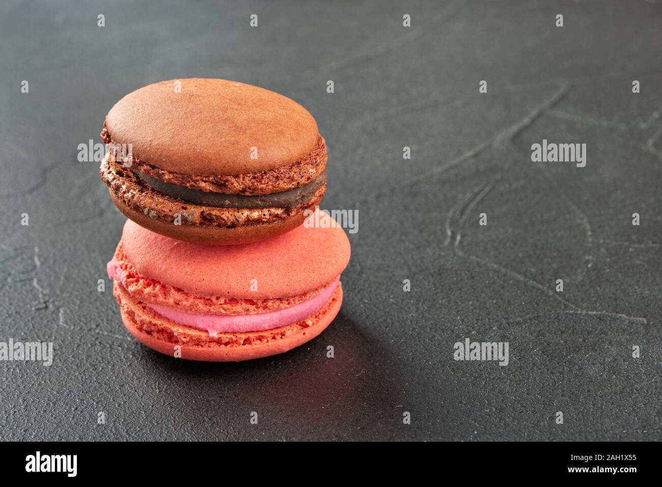 Schokolade und Himbeere Makrone auf einem dunklen konkreten Hintergrund Stockfoto