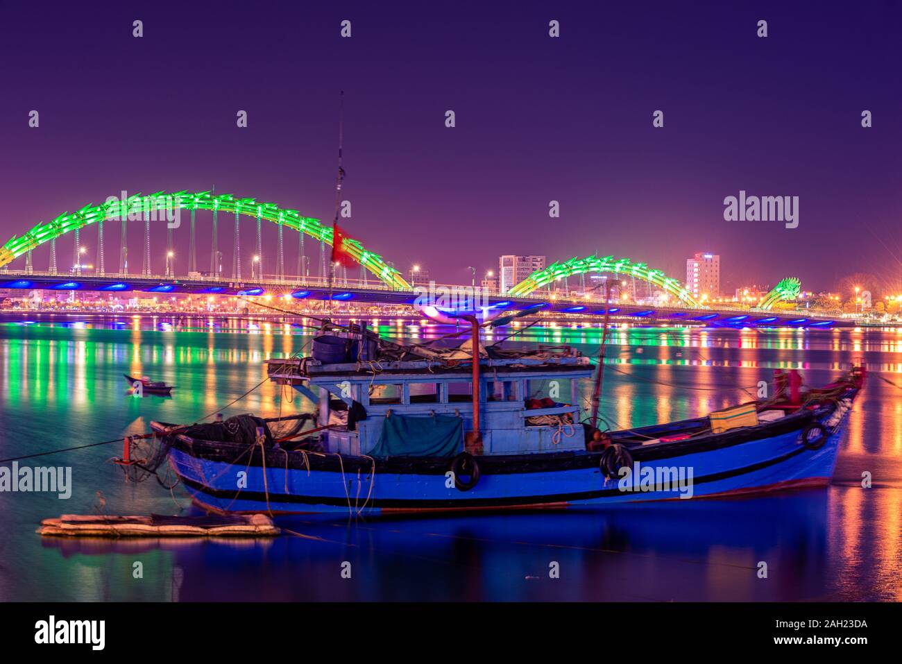 Vietnamesische Fischerboot auf den Fluss Han und Dragon Brücke, wie vom Ufer aus in der Nacht Da Nang, Vietnam beobachtet Stockfoto