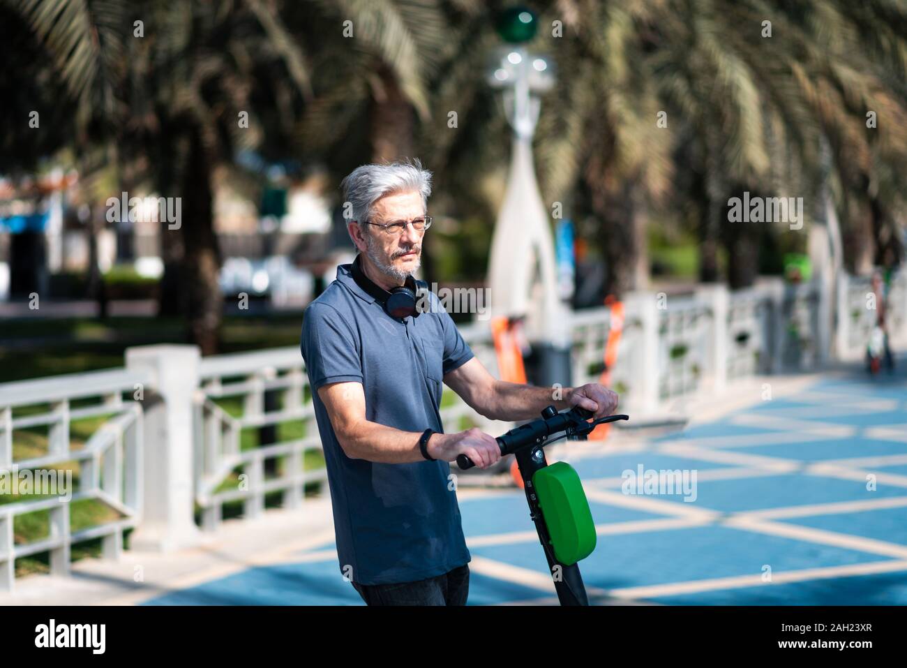 Senior mit elektrischer Roller für den Transport in einer modernen Stadt Umgebung Stockfoto