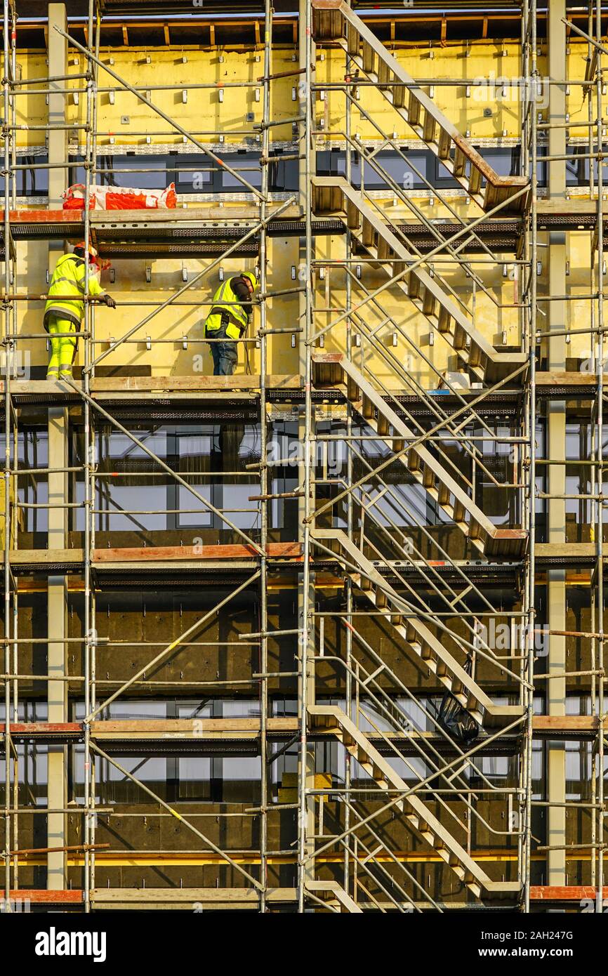 Gerüst rund um das Haus Wärmedämmung der Fassade zu installieren, Arbeitnehmer in Sicherheitswesten und Helme Stockfoto