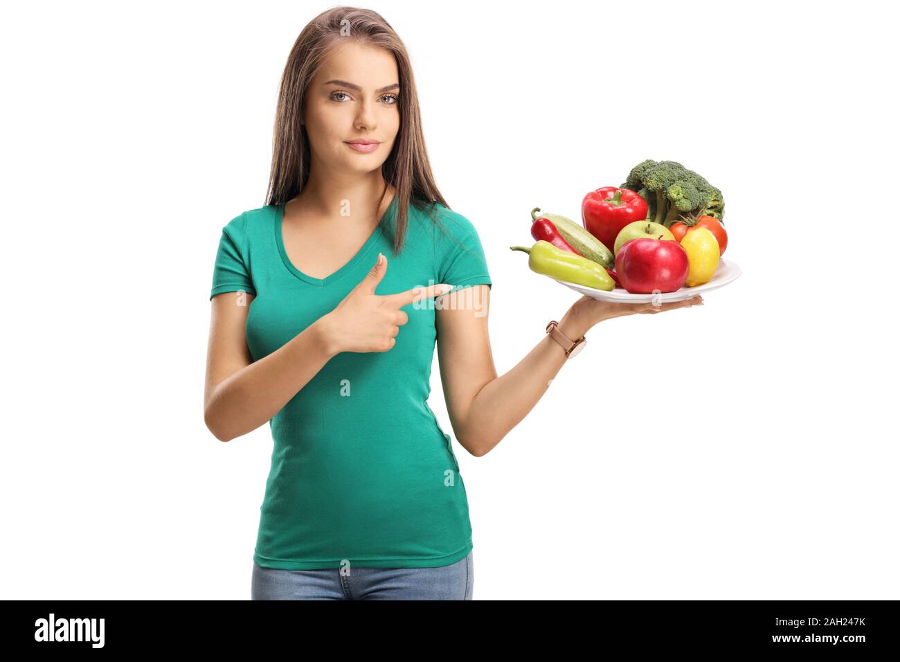 Schöne junge Frau mit einem Teller mit Früchten und Gemüse und zeigt auf weißem Hintergrund Stockfoto