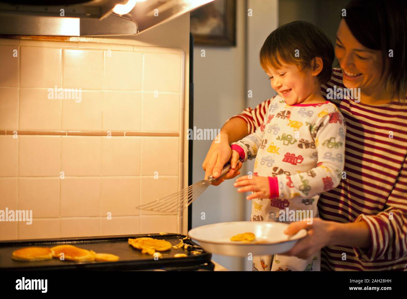 Mutter und Sohn kochen Pfannkuchen zusammen. Stockfoto