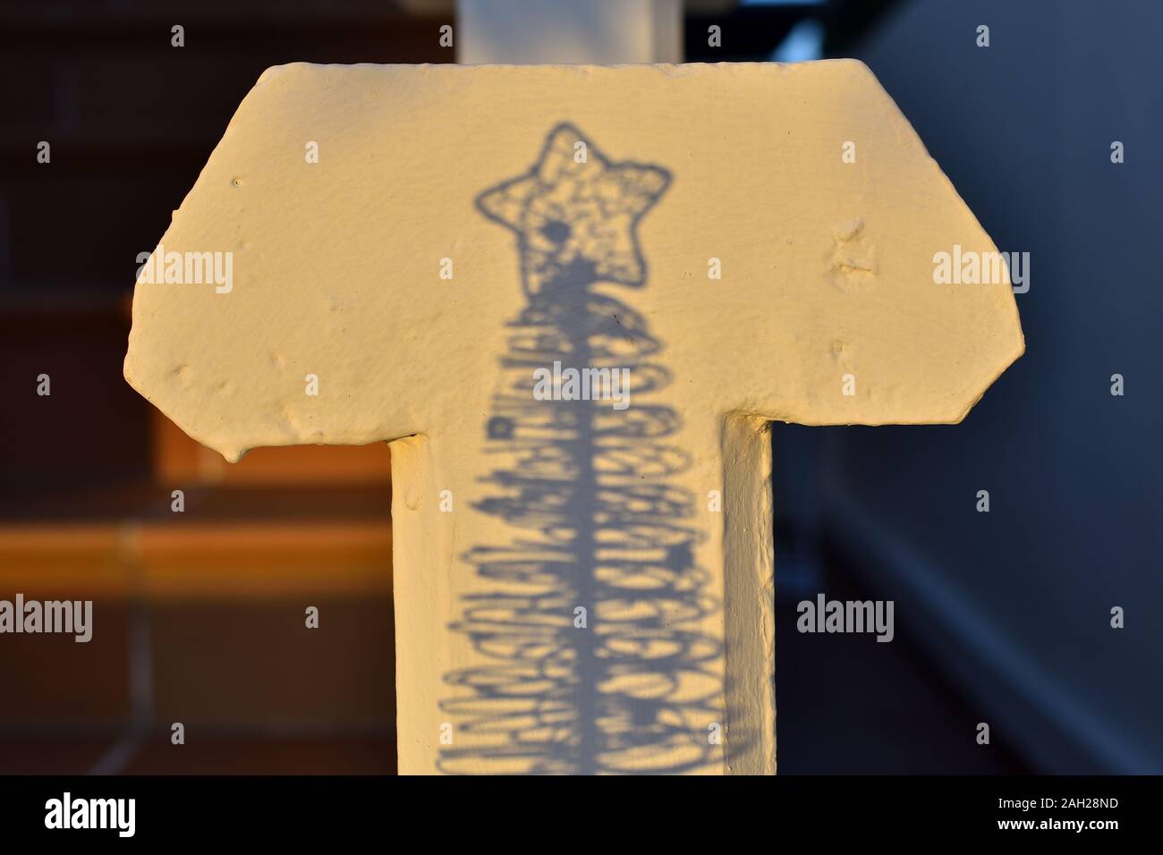 Der Anfang und das Ende: Schatten eines kleinen Weihnachtsbaum auf einem kreuzförmigen Balustrade Stockfoto