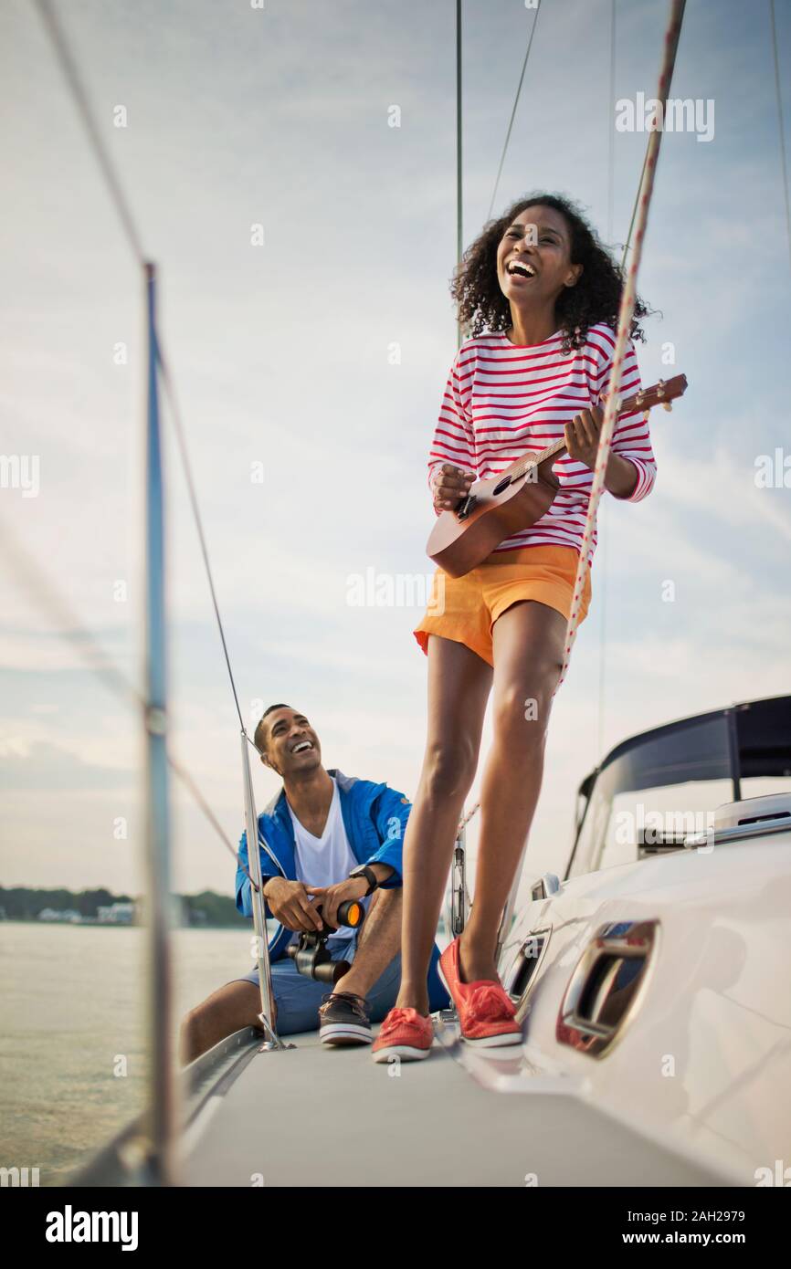 Glückliches junges Paar, das Spaß spielen der Ukulele auf einem Segelboot Stockfoto
