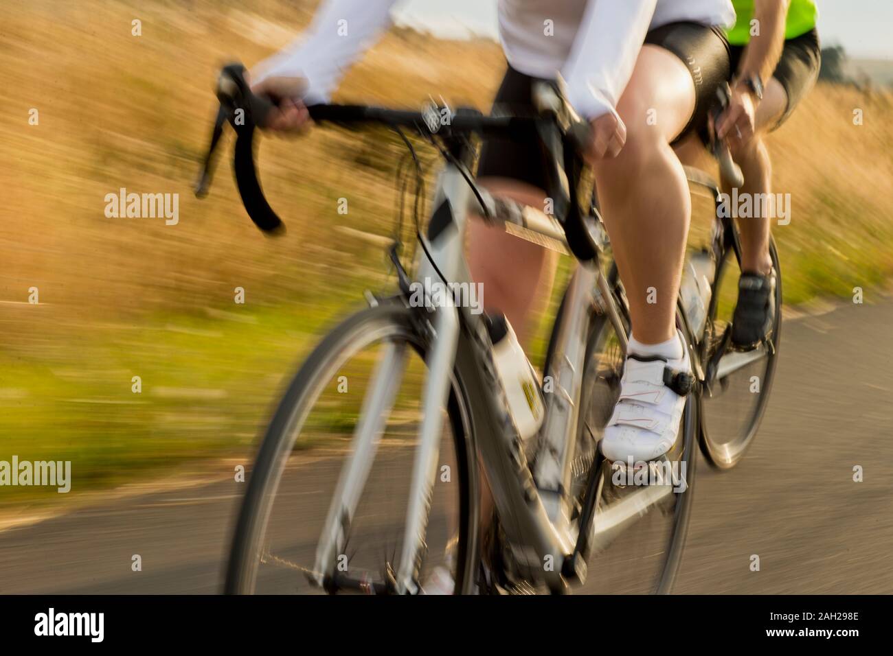 Reifes Paar Radfahren entlang einer Landstraße Stockfoto