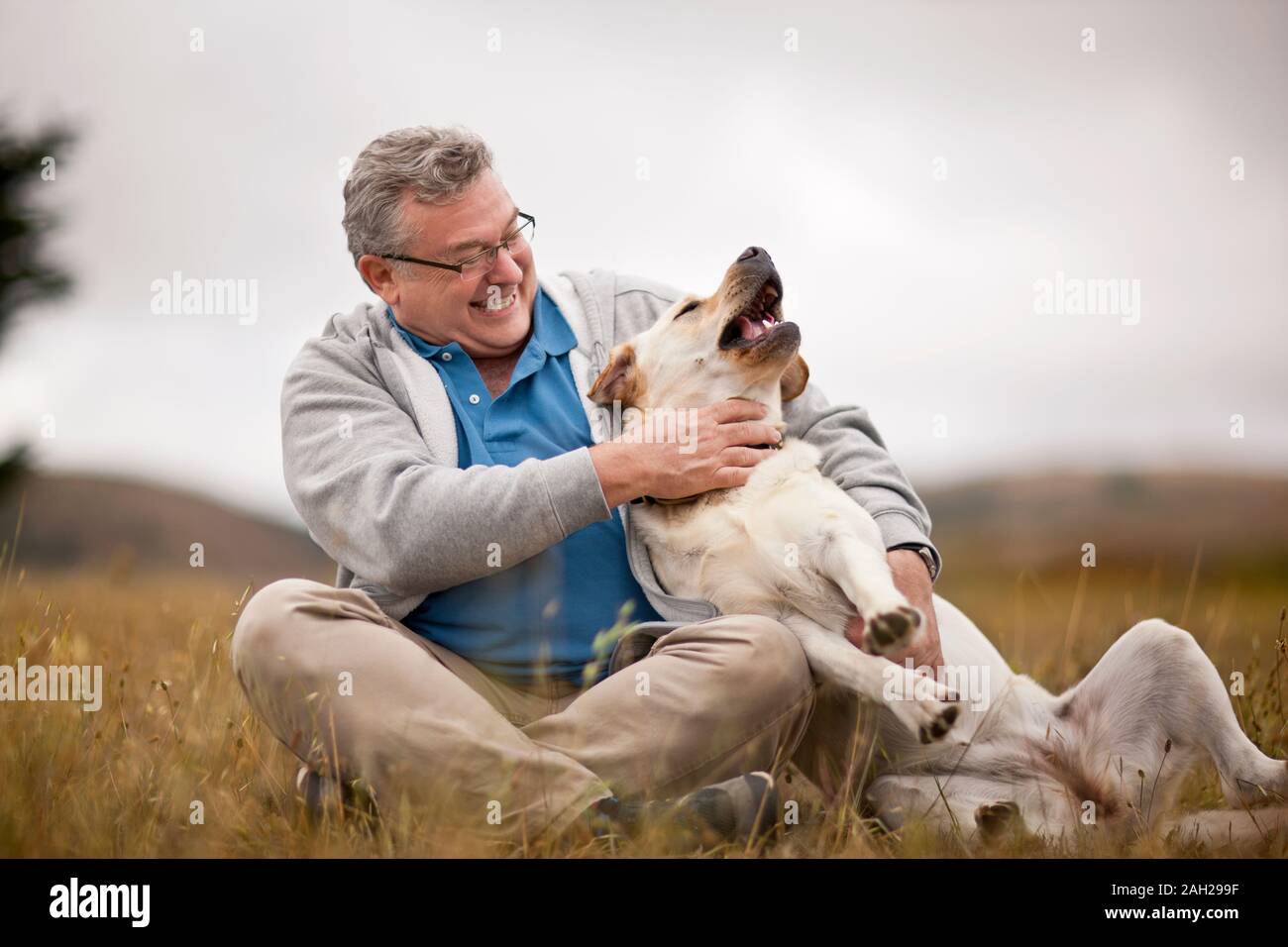 Lächelnd reifer Mann spielt mit seinem Hund in einem ländlichen Bereich Stockfoto
