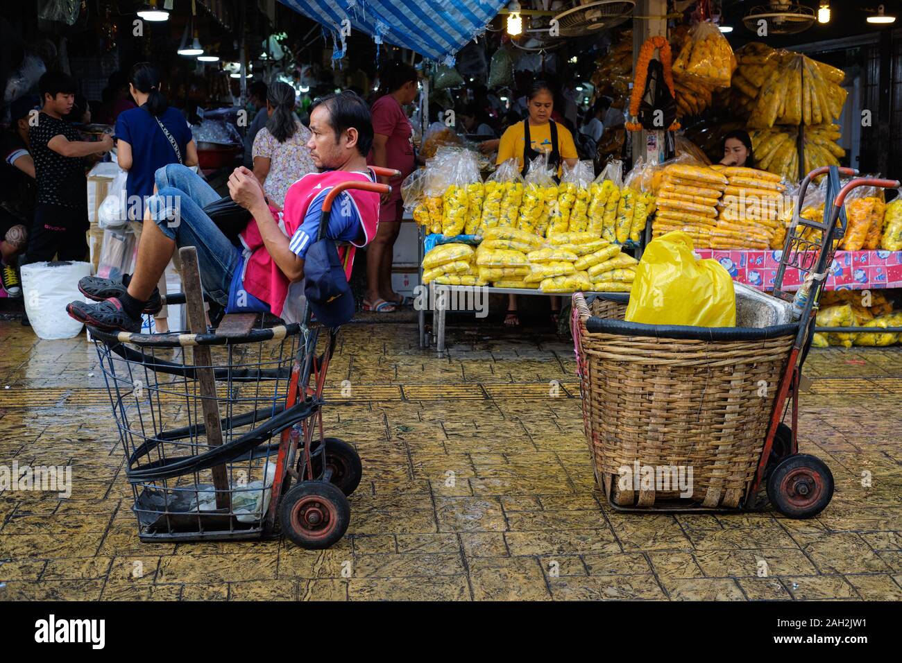 Ein Portier an (Markt) Pak Klong Talaat) Talad) in Bangkok, Thailand, einen gemütlichen Ruhelage in einem Korb Katze gefunden Stockfoto