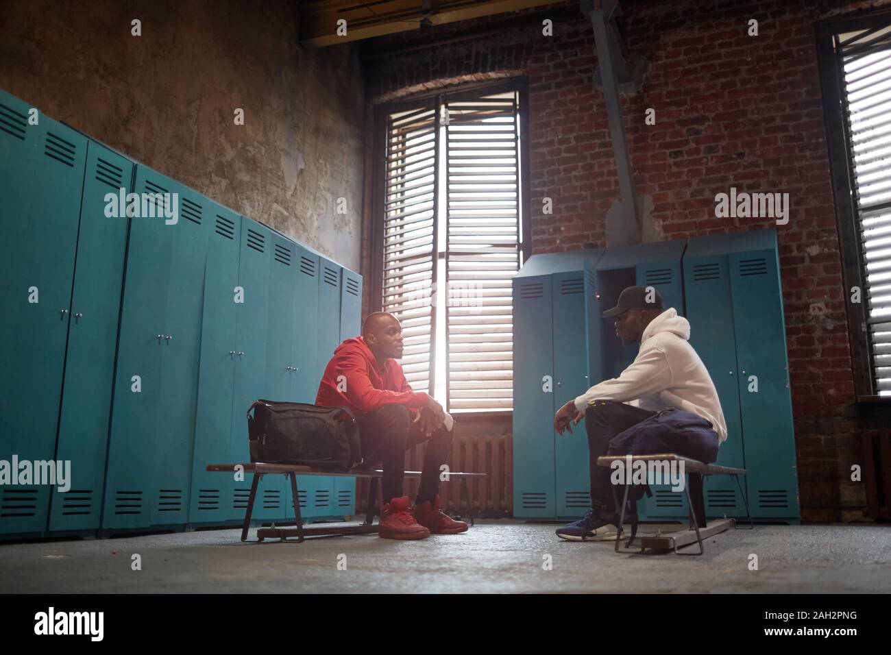 Zwei afrikanische Männer in Sport Kleidung sitzt auf der Bank und sprechen miteinander in der Umkleide Stockfoto