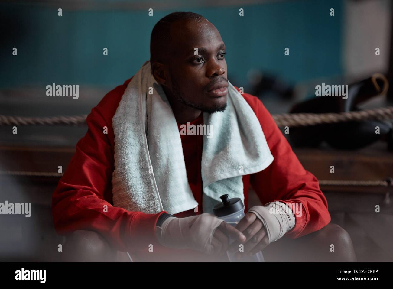 Afrikanischer junge Sportler sitzt auf der Bank und Trinkwasser er Ausruhen nach Sport Training Stockfoto