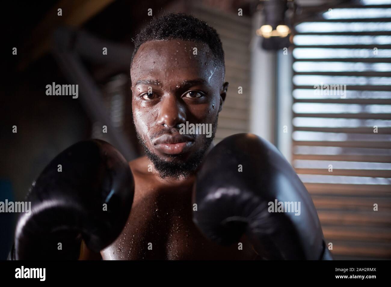 Portrait der Afrikanischen jungen Sportler in boxhandschuhe an der Kamera während des Trainings in der Turnhalle auf der Suche Stockfoto