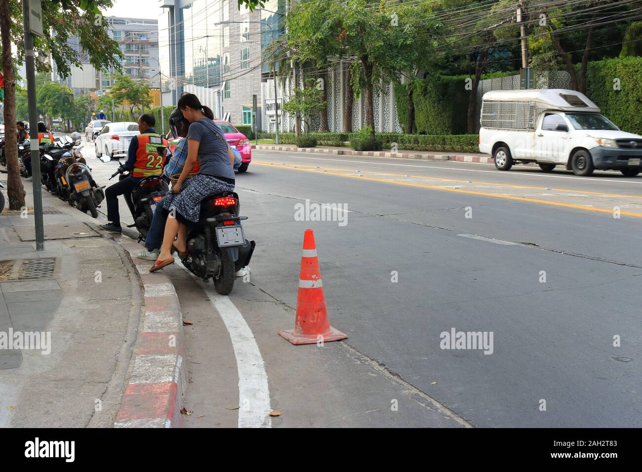 Bangkok, Thailand-December 23, 2019: Ein weiblicher Fahrgast sitzen auf sozius eines Motorrades Taxi immer bereit für eine Fahrt am Motorrad Taxi Warteschlange. Stockfoto