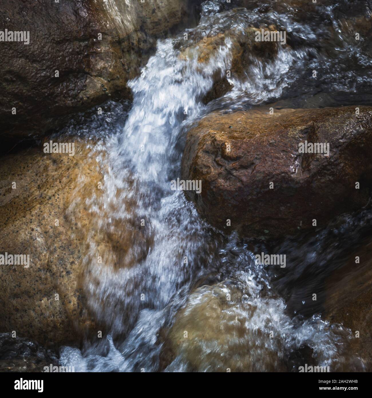 Wasser fließt durch Felsbrocken in einem Stream. Stockfoto