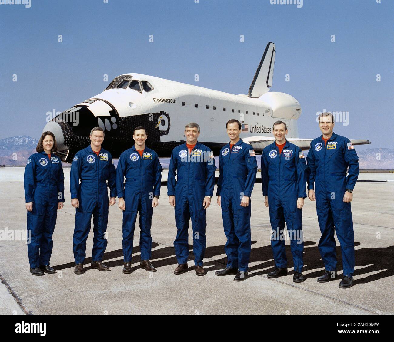 (16 Jan. 1992) - - - Diese sieben NASA-Astronauten sind derzeit für den ersten Flug des Space Shuttle Endeavour, im Hintergrund zu sehen. Daniel C. Brandenstein, Mitte, wird Mission Commander; und Kevin S. Chilton, dritter von rechts, ist Pilot. Mission Spezialisten sind, nach rechts, Kathryn Thornton, Bruce Melnick, Pierre Thout, Thomas Akers und Richard Hieb. Links Stockfoto