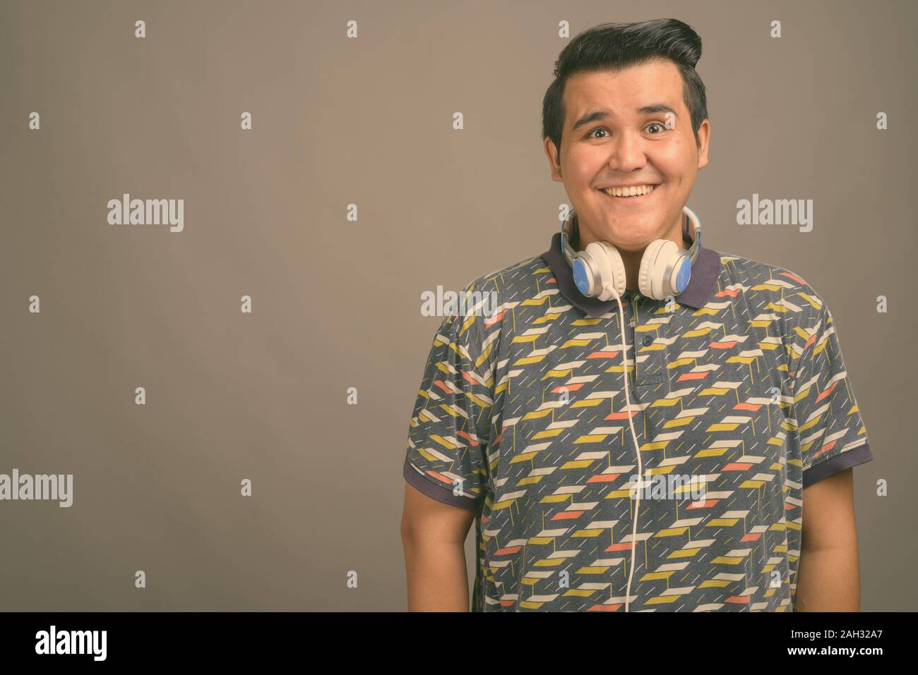 Studio shot Junger multi-ethnische Mann Musik gegen grauer Hintergrund Stockfoto