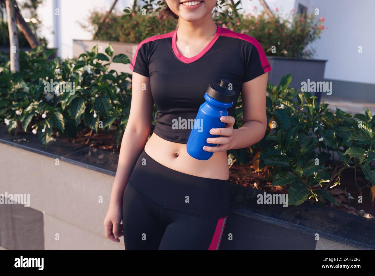 Frau mit blauen Flasche während des Trainings im Park. Gesund und Sport Konzept. Stockfoto
