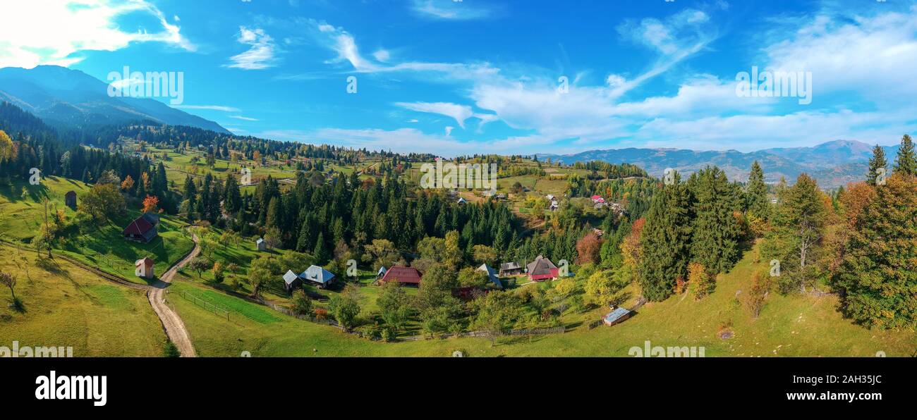 Antenne Panoramablick auf eine ländliche Region mit Bauernhöfen, Feldern und die Karpaten Gebirge im Hintergrund. Borsa, Banat, Rumänien. Stockfoto