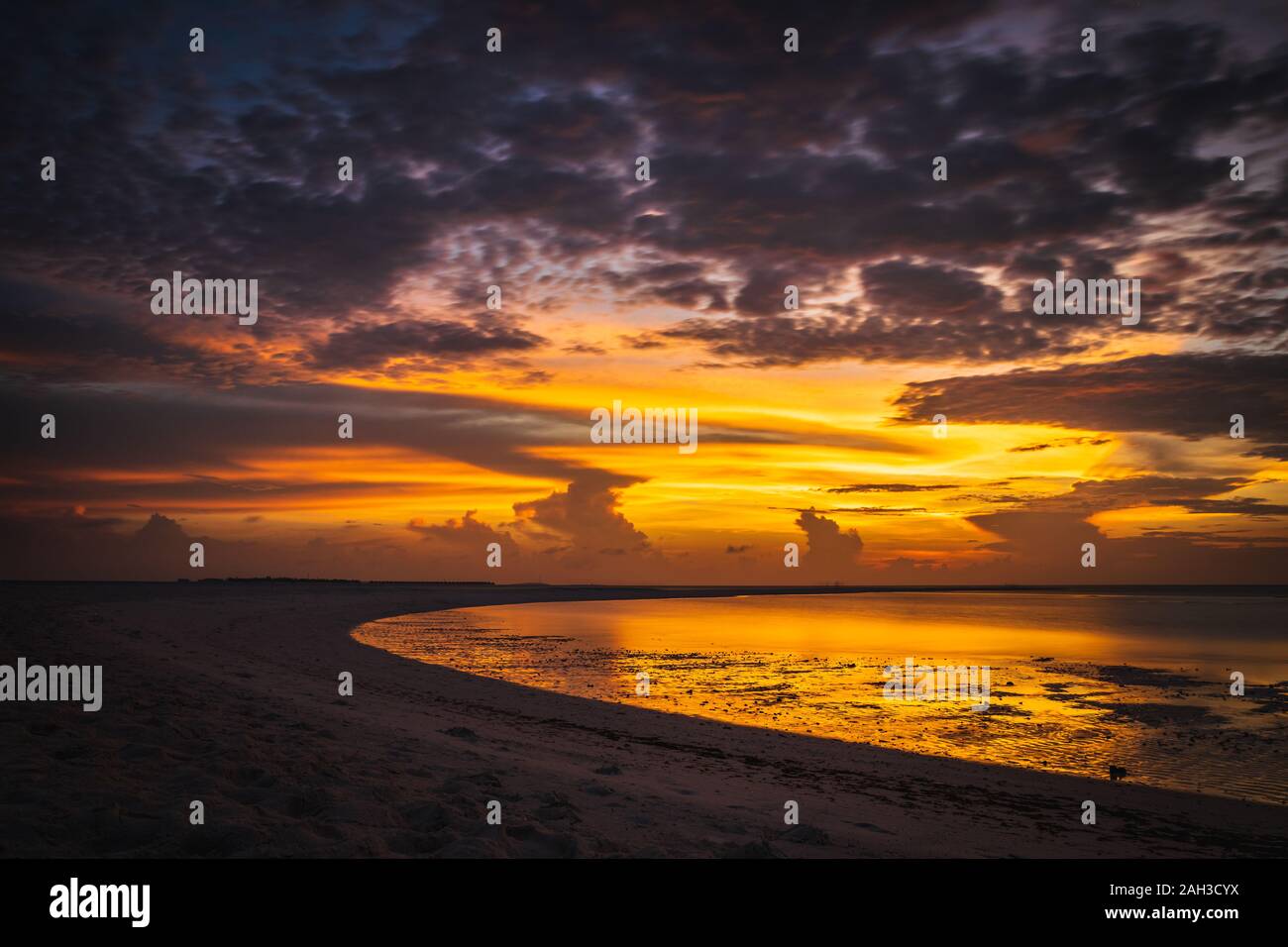 Sonnenuntergang auf den Malediven mit Reflexion der Sonne im Wasser und blau und orange farbige Wolken im Himmel Stockfoto