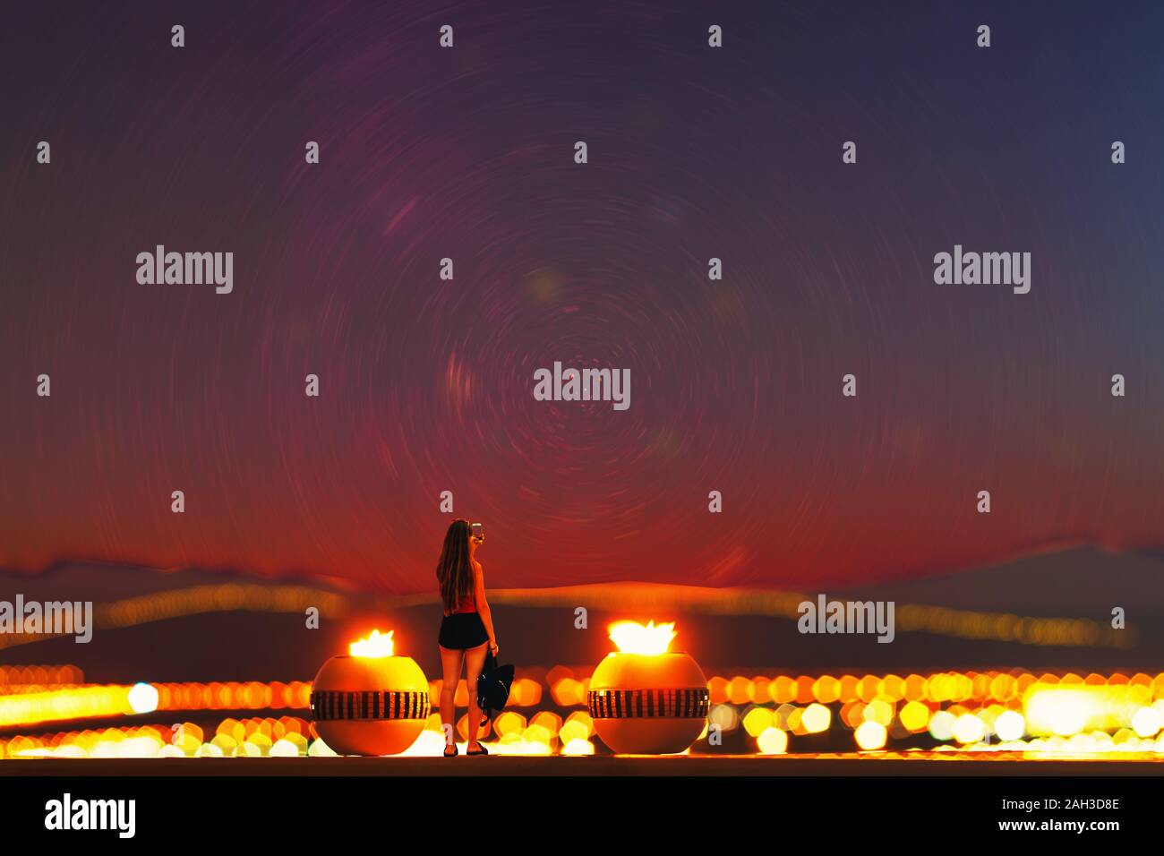 Ein Mädchen ein Bild des Universums in der Nacht in zwischen zwei Runden brennenden dekorative Steine mit dem Panoramablick auf die Berge. Märchen & Ventilator Stockfoto