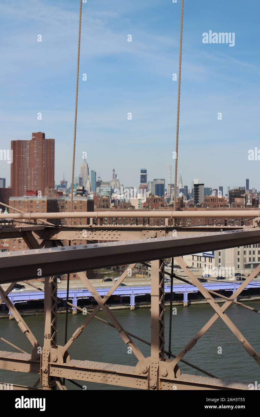 Detail der Brooklyn Bridge mit Blick auf die Skyline Manhattans und das Empire State Building in der Ferne. New York City, New York State, USA. Stockfoto