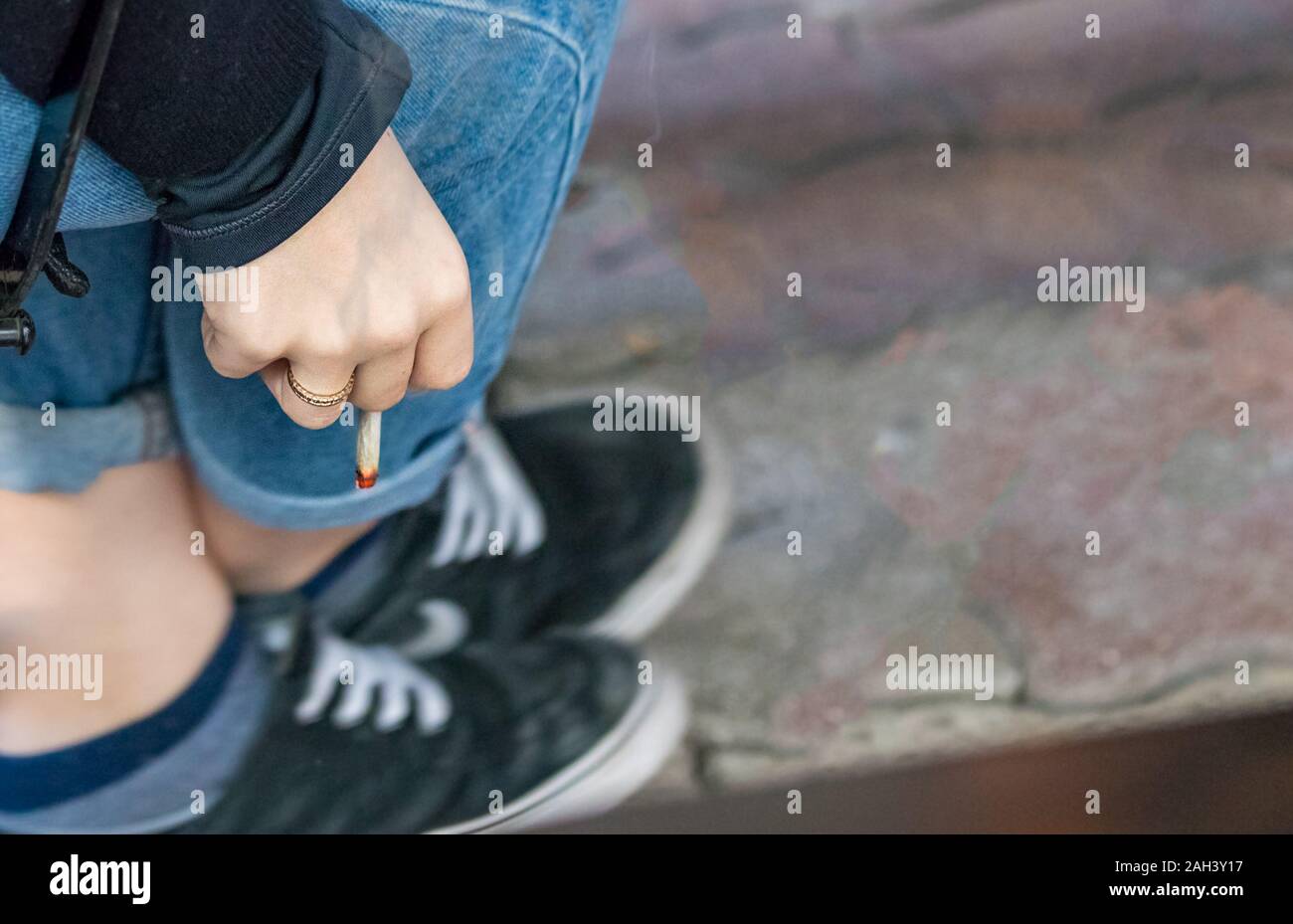 Die Hand ein junges Mädchen mit einer Zigarette im Freien sitzen Stockfoto