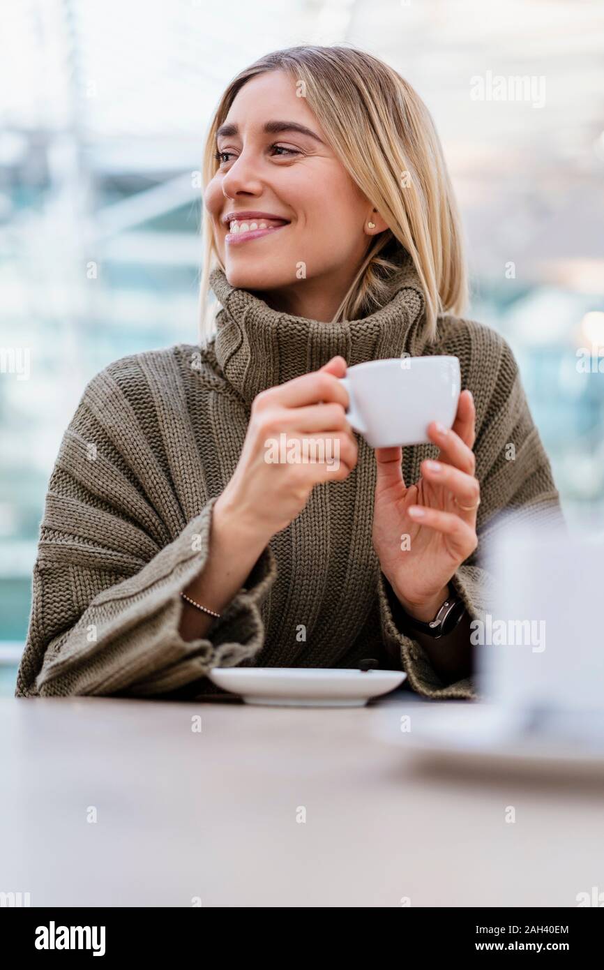 Porträt eines lächelnden jungen Frau mit Tasse Kaffee weg schauen Stockfoto