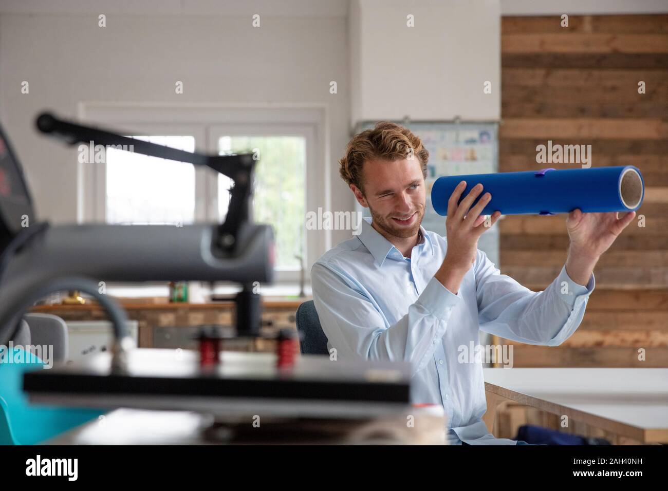 Junge Unternehmer in seinem Büro, schauen durch blaue Leitung Stockfoto