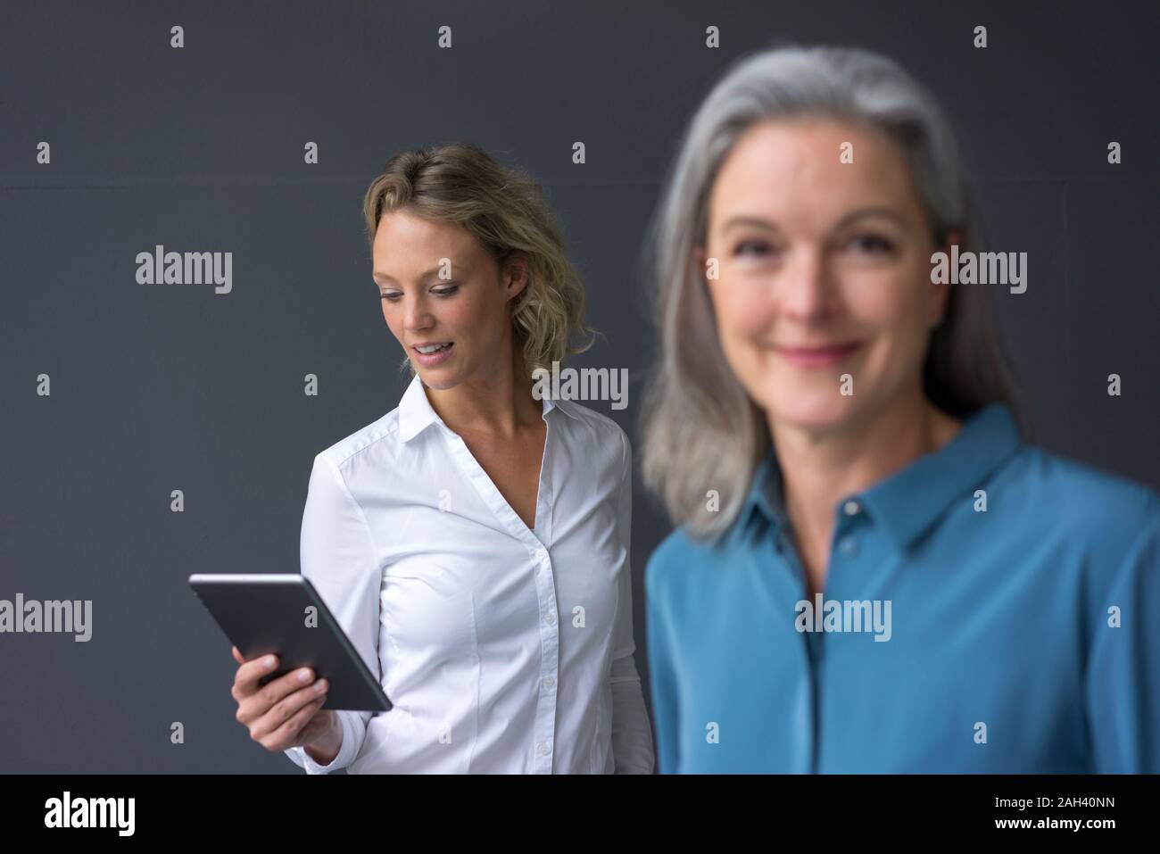 Junge Geschäftsfrau mit Tablet mit Reife Geschäftsfrau im Vordergrund Stockfoto