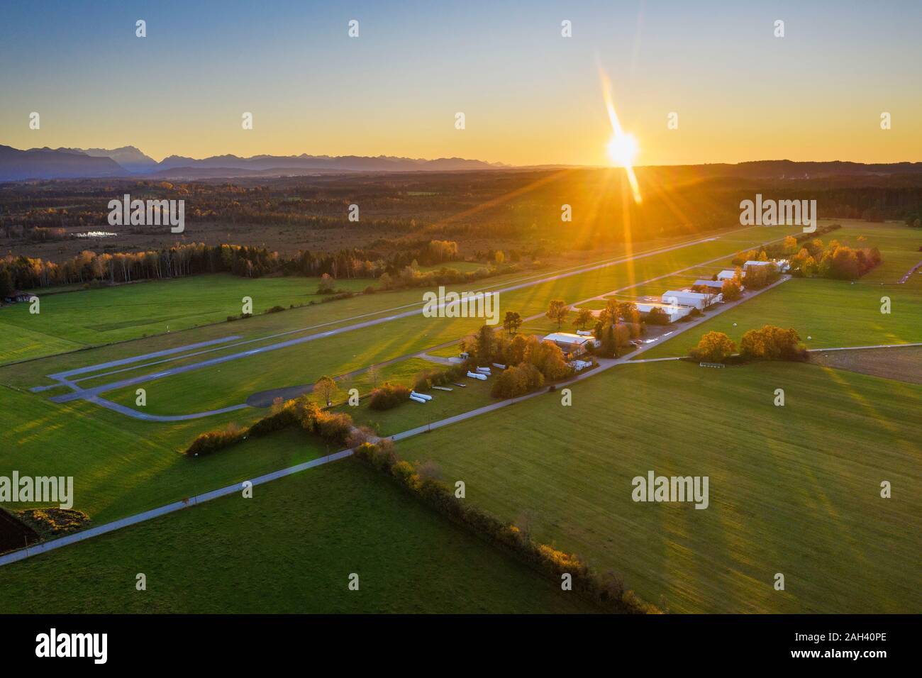 Deutschland, Bayern, Oberbayern, toelzer Land, Konigsdorf, Luftaufnahme von Feldern und Dorf bei Sonnenuntergang Stockfoto