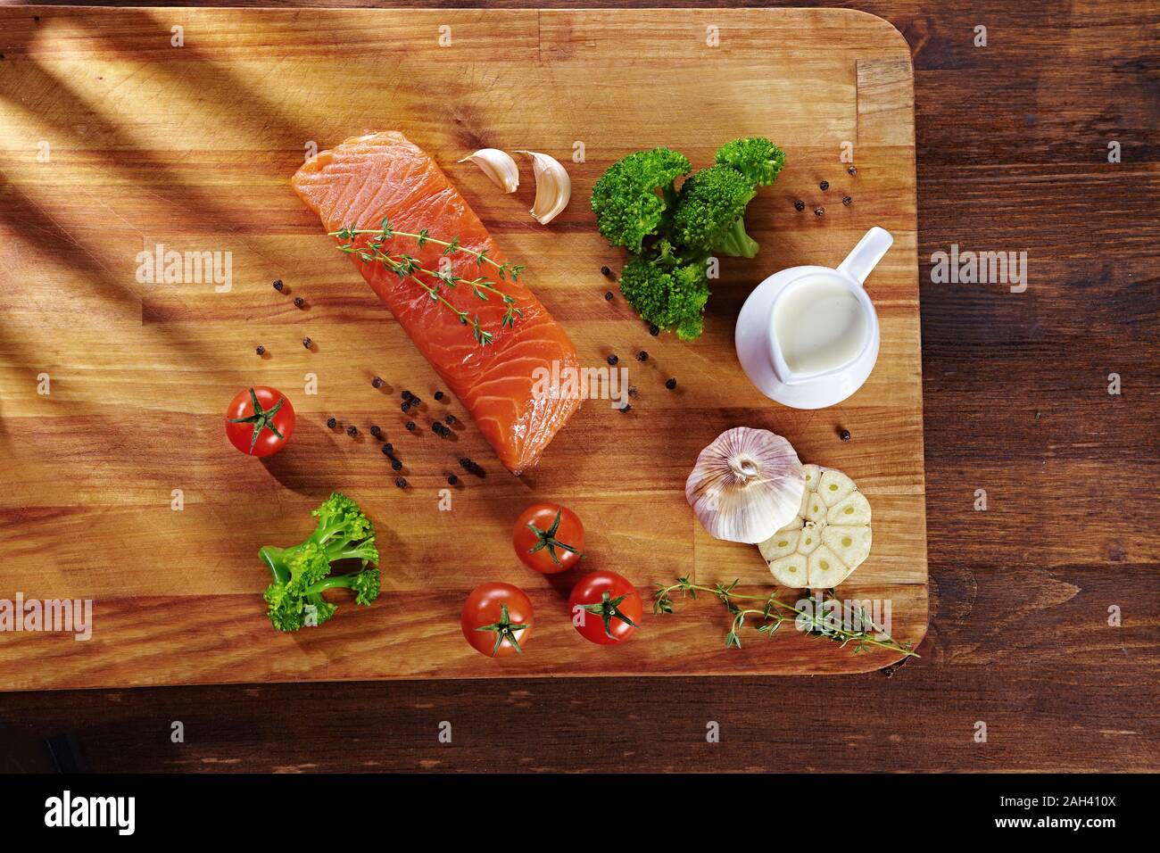 Set von gesunden Krebsnahrung auf Holztisch. Roter Lachsfisch, Brokkoli, Knoblauch, Milch, Pfeffer und Tomaten verstreut um den Tisch. Gesunde Mahlzeit Stockfoto