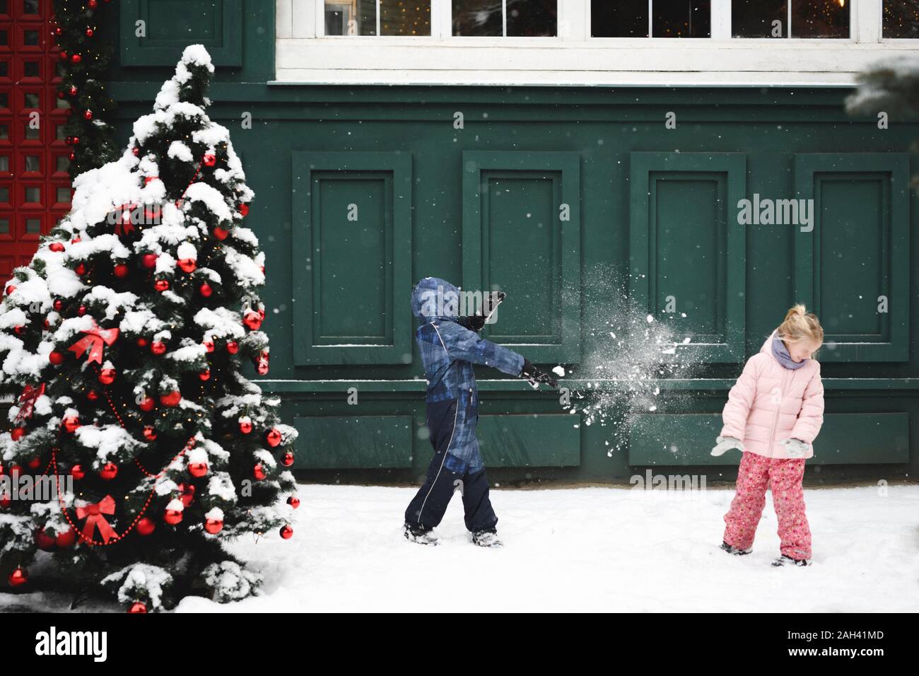 Geschwister in eine Schneeballschlacht an Weihnachten Zeit Stockfoto