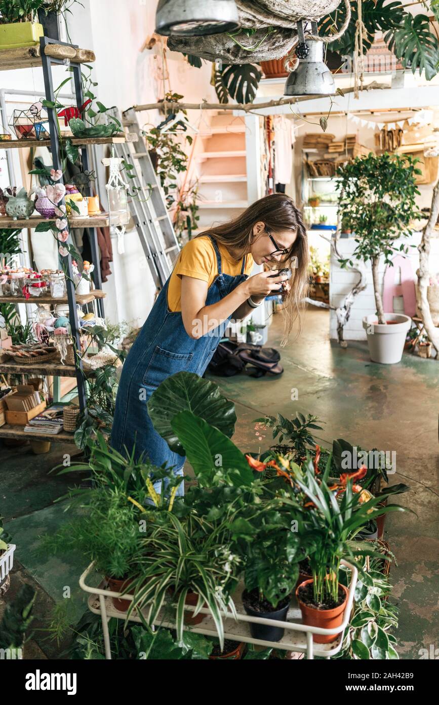 Junge Frau, die Bilder von Pflanzen in einem kleinen Garten shop Stockfoto