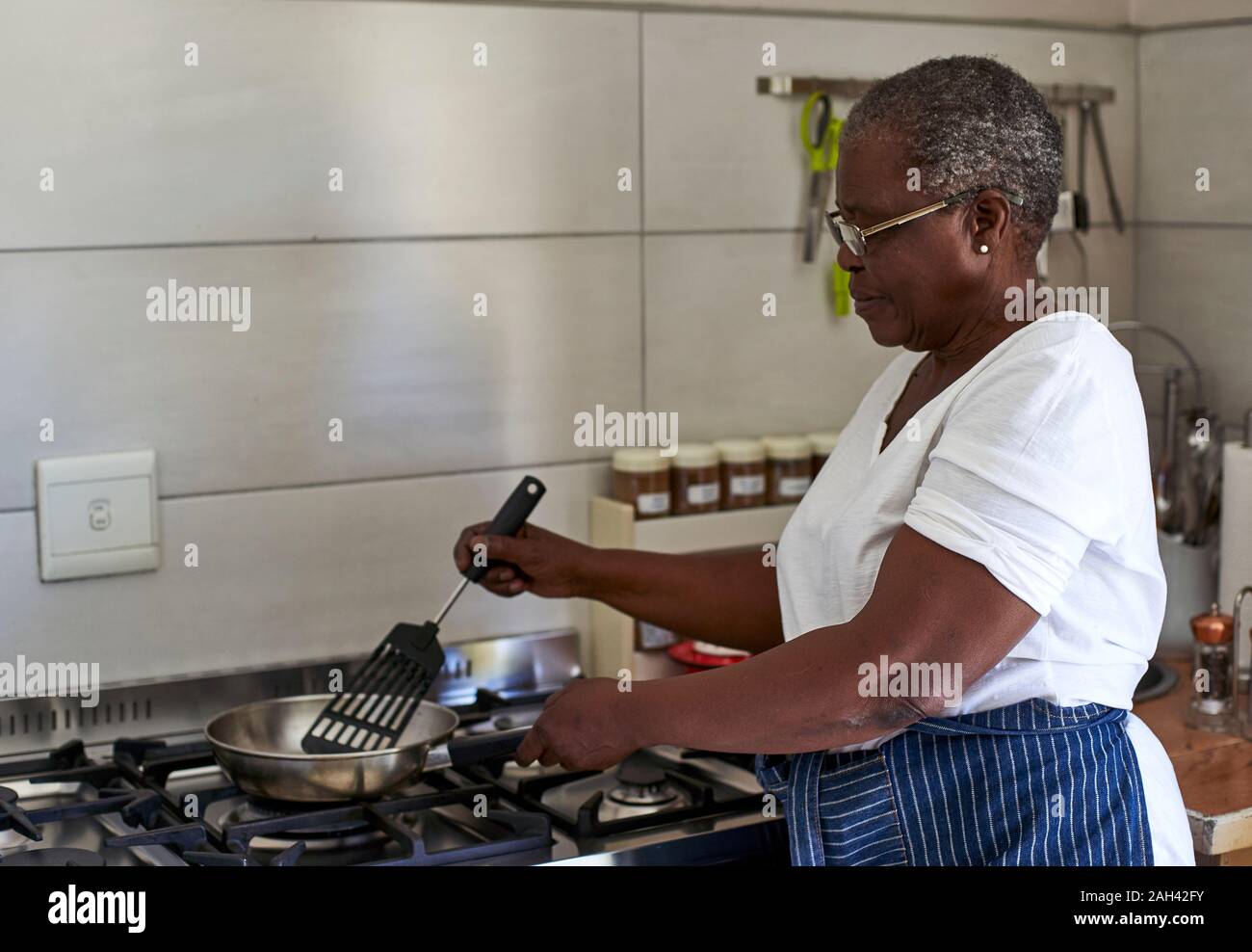 Ältere Frau kochen auf Gas Herd in der Küche Stockfoto