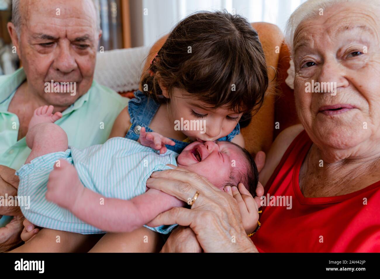 Großeltern mit kleinen Mädchen und Babys zu Hause Stockfoto