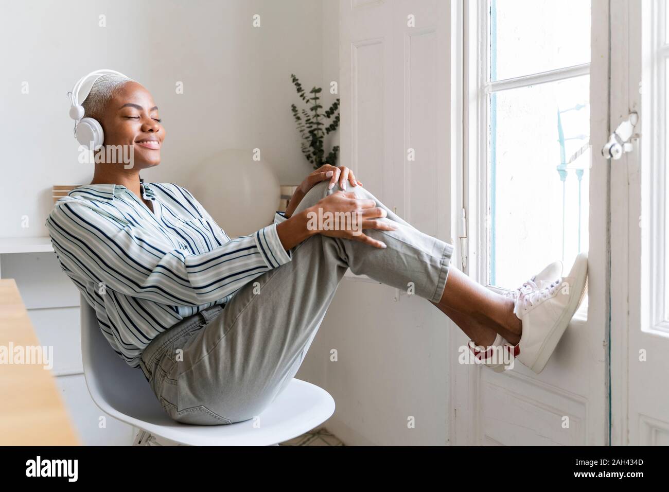 Lächelnden jungen Frau Hören von Musik am Fenster Stockfoto
