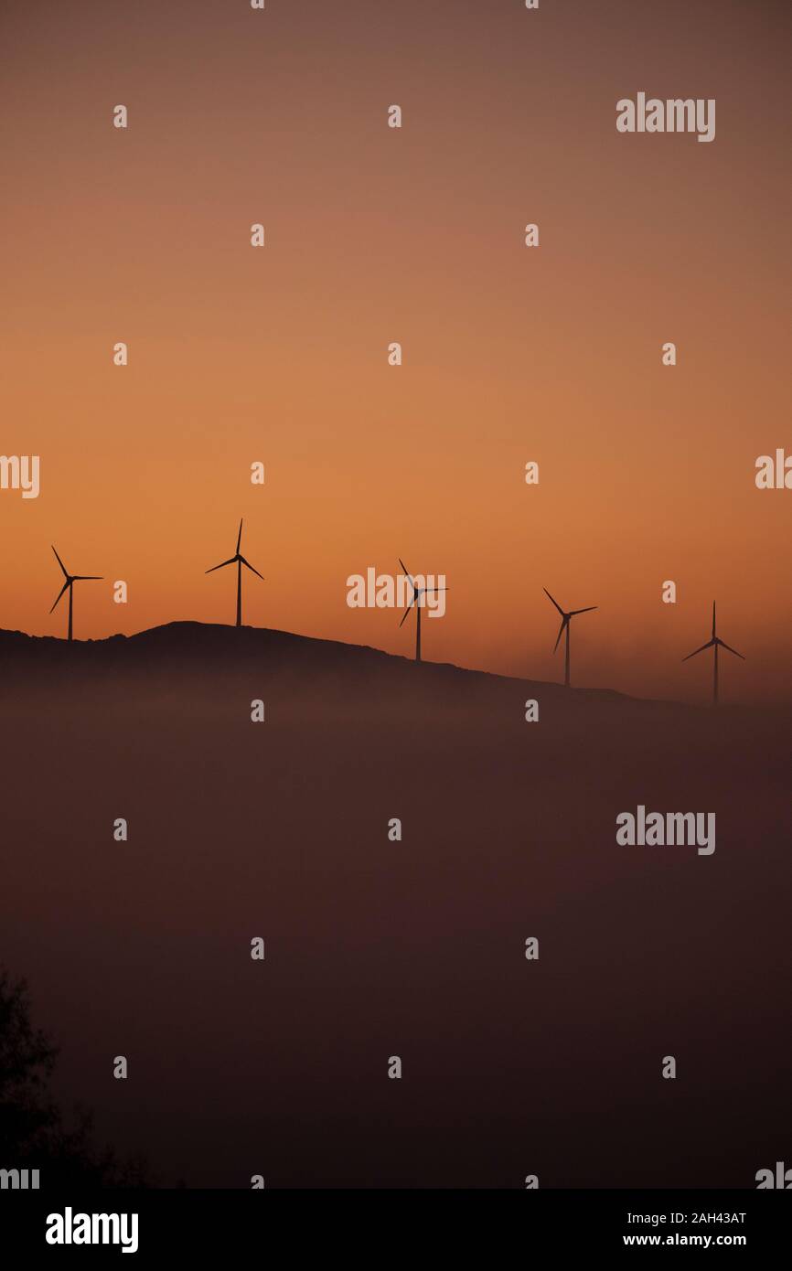 Spanien, Provinz Cadiz, Tarifa, Silhouetten von Windenergieanlagen gegen Moody Sky At foggy Dawn stehend Stockfoto