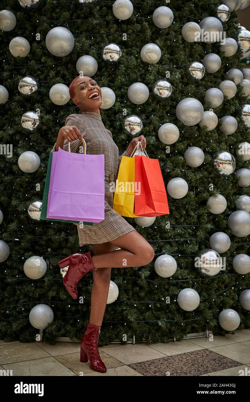 Frau mit bunten Einkaufstaschen am Weihnachtsbaum Stockfoto