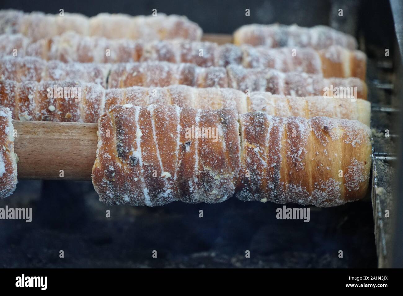 Vorbereitung der traditionellen tschechischen Street Food Trdelnik auf Holzspieße über glühende Kohlen auf Weihnachtsmarkt gerollt Stockfoto