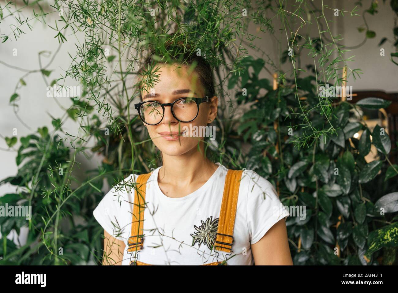 Porträt einer jungen Frau, umgeben von Pflanzen Stockfoto