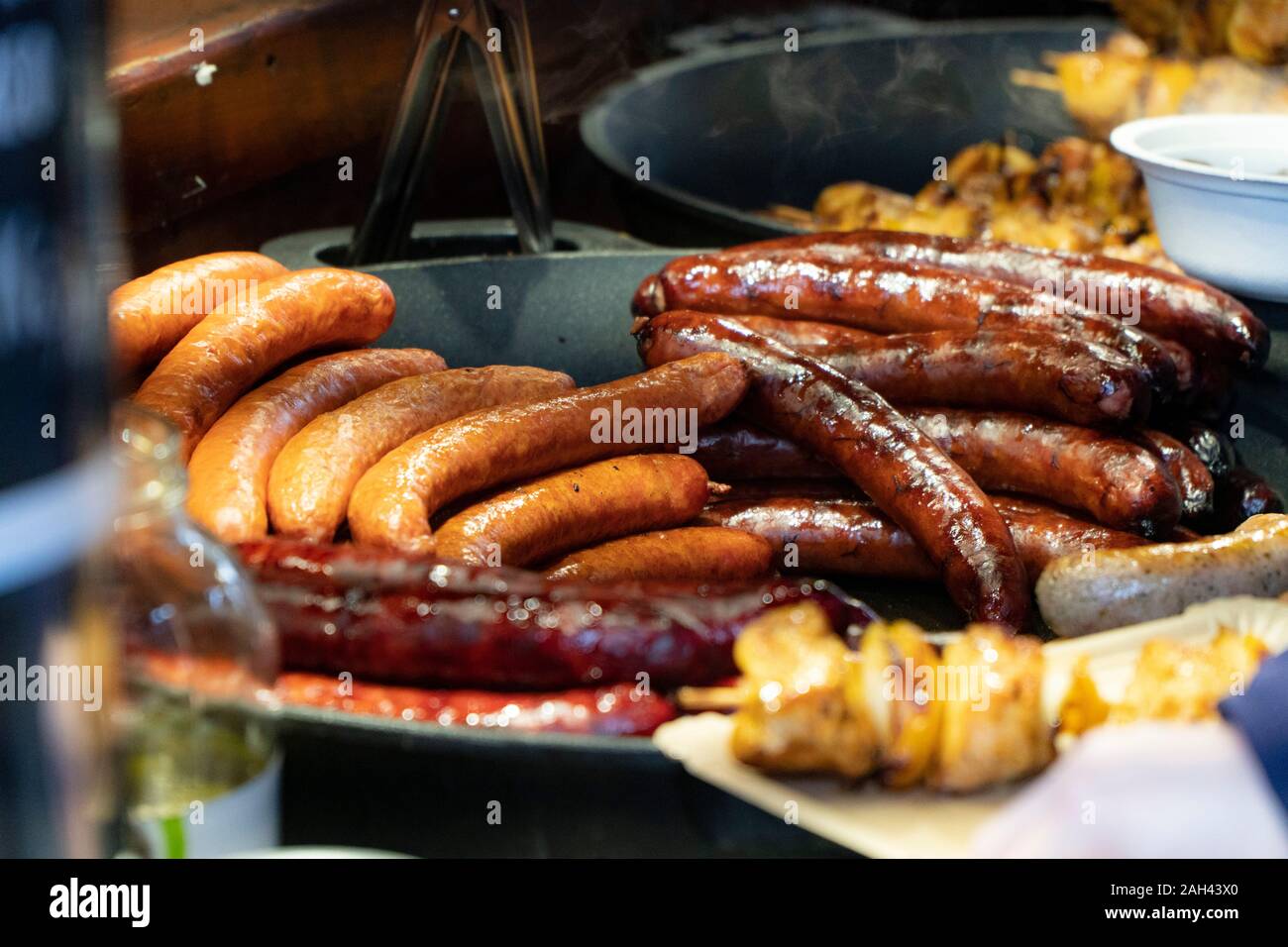 Prag, Tschechische Republik 2019: Traditionelle Hot dog Vorbereitung auf die Kohle Feuer auf der Straße während des Weihnachtsmarktes Stockfoto