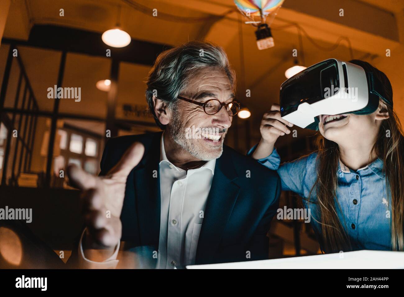 Happy senior buisinessman und Mädchen mit VR-Brille mit Heißluft-Ballon im Büro Stockfoto