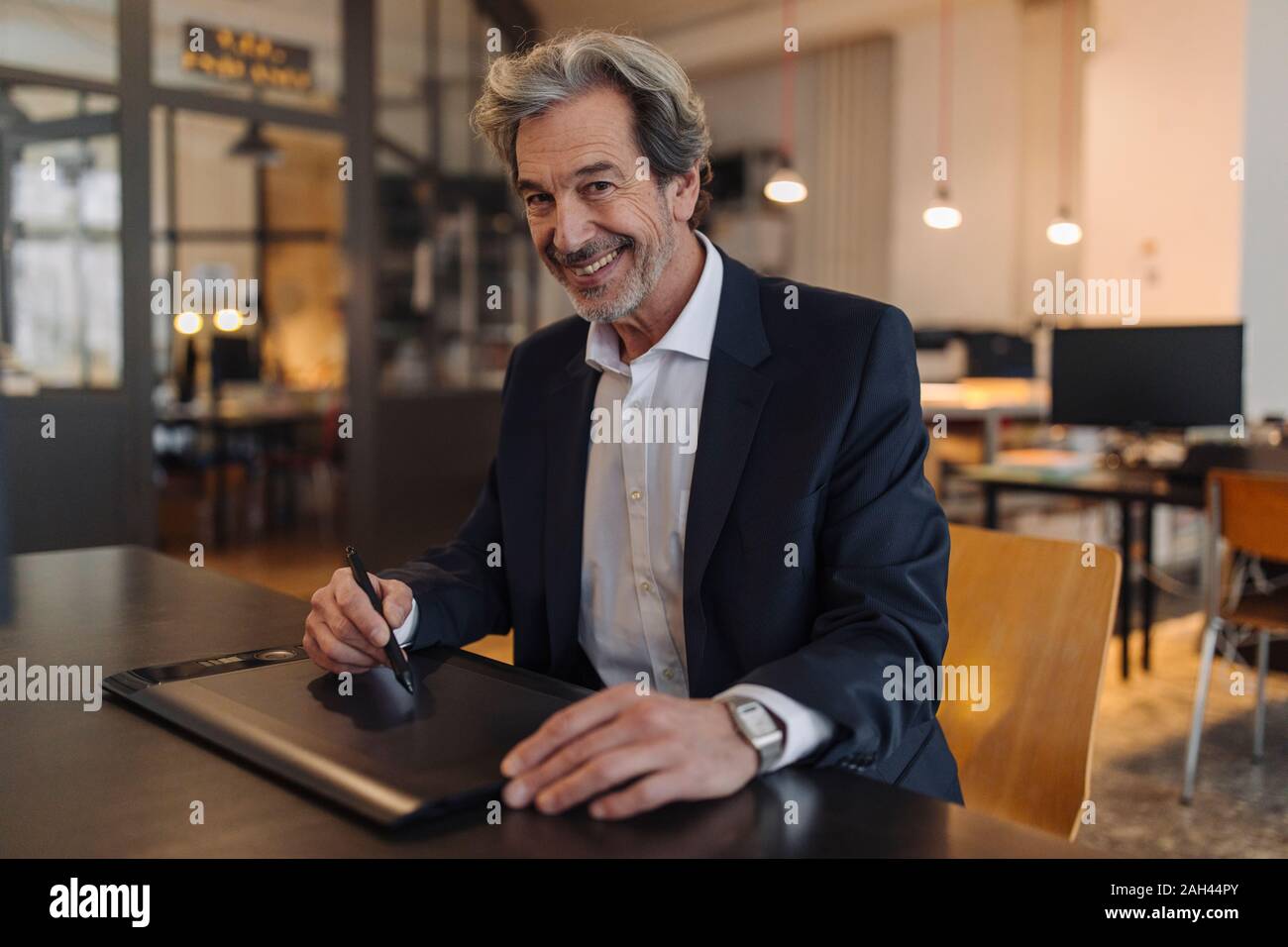 Portrait von lächelnden älteren Geschäftsmann mit grafiktablett am Schreibtisch im Büro Stockfoto