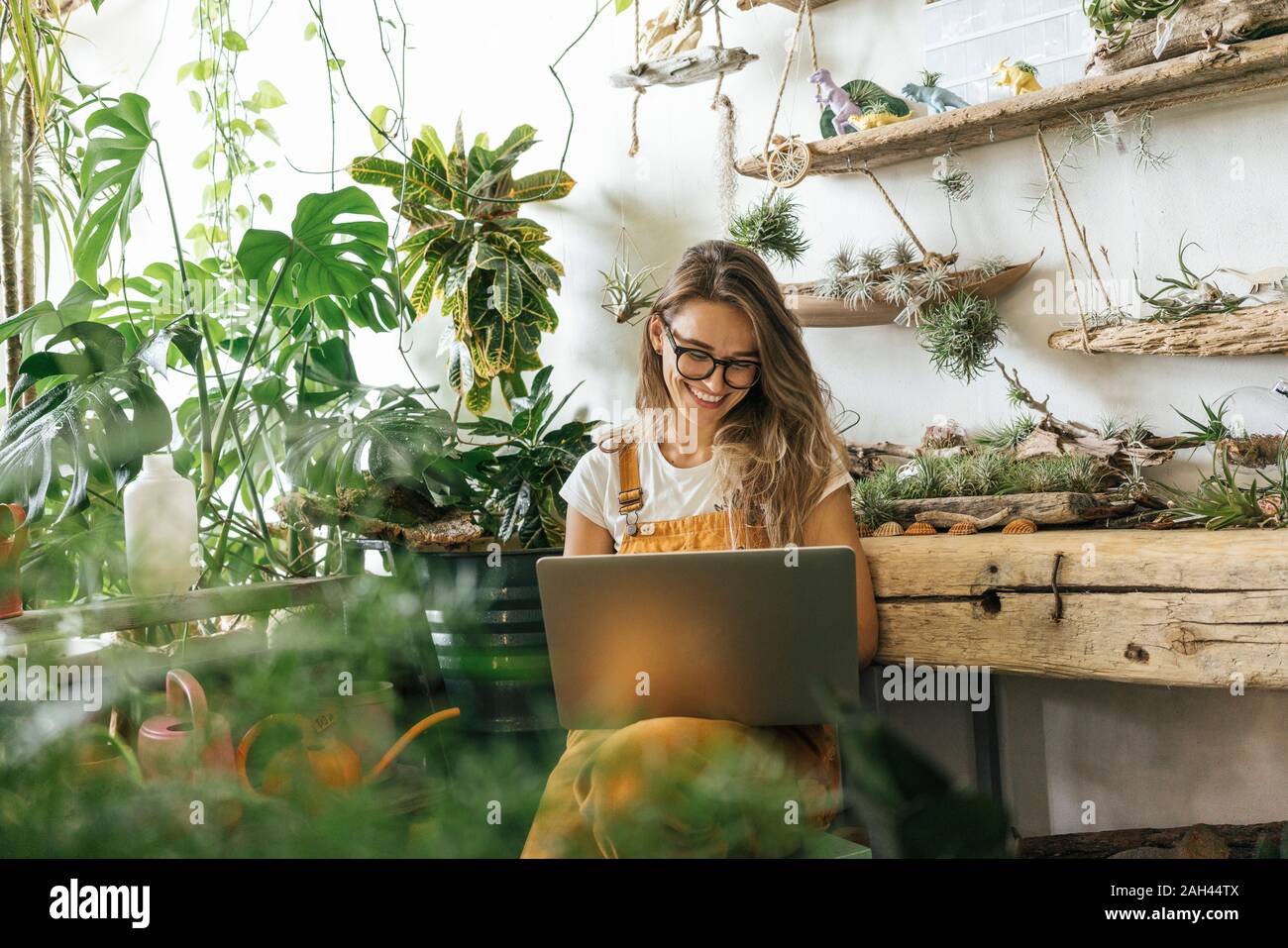Glückliche junge Frau mit Laptop in einem kleinen Garten shop Stockfoto