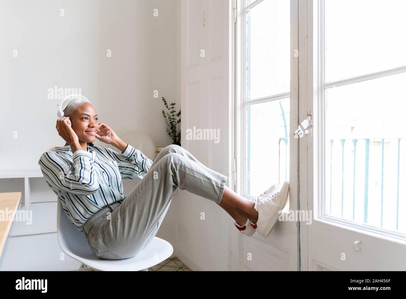 Lächelnden jungen Frau Hören von Musik am Fenster Stockfoto