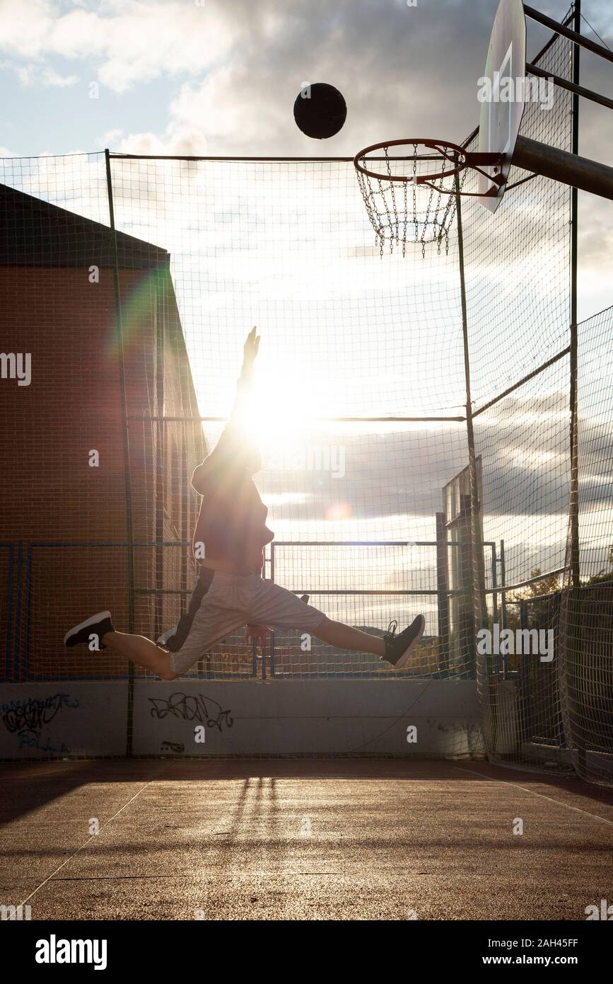 Teenager spielen Basketball, dunking gegen die Sonne Stockfoto