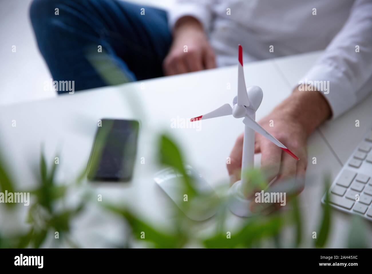 Nahaufnahme der Mann mit der Hand am Wind Turbine Modell auf Tisch Stockfoto