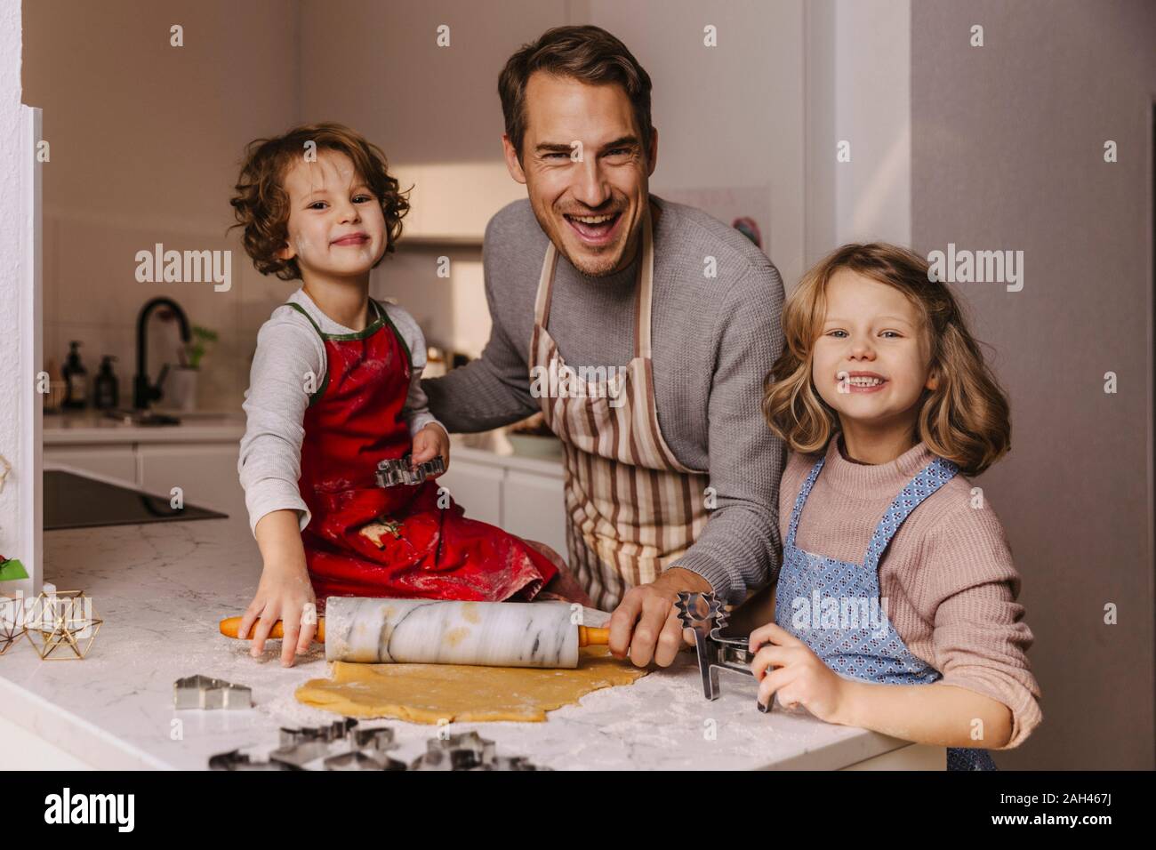 Gerne Vater mit zwei Töchtern Vorbereitung Weihnachtsplätzchen in der Küche Stockfoto