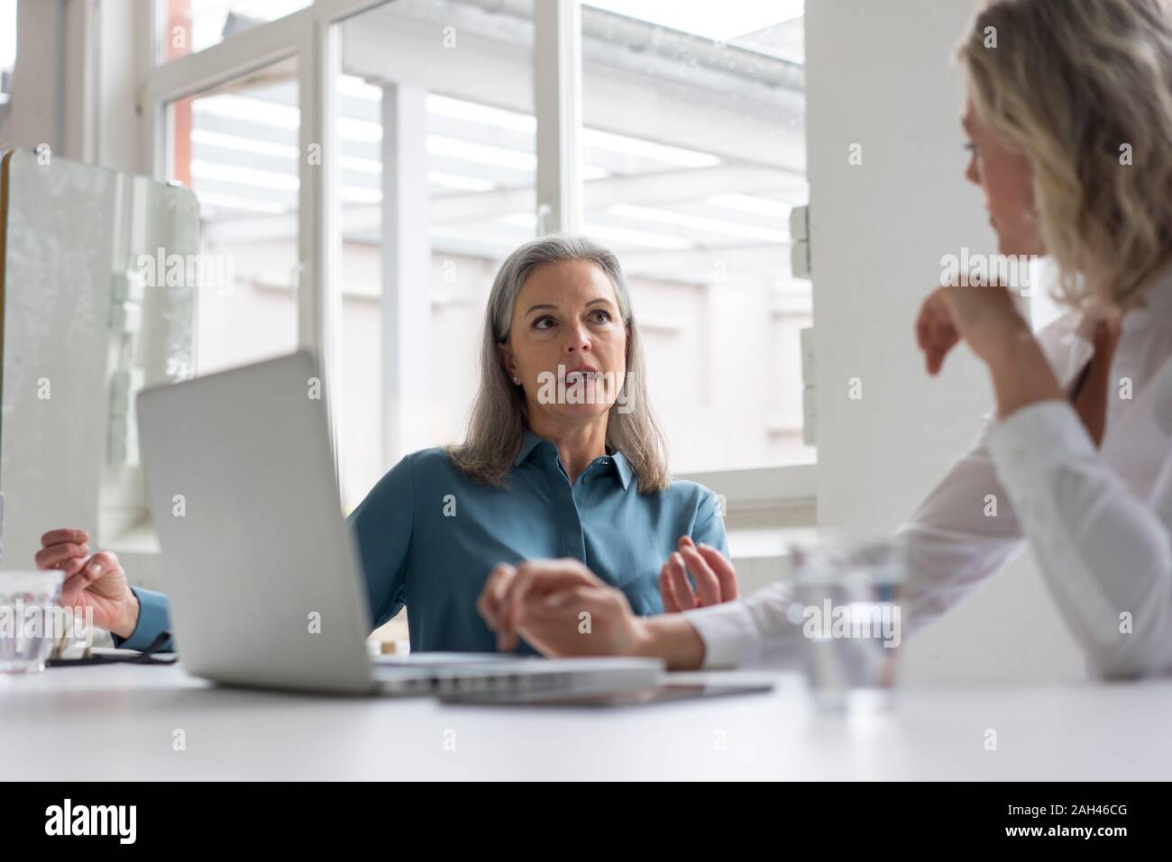 Zwei Unternehmerinnen diskutieren am Schreibtisch im Büro Stockfoto